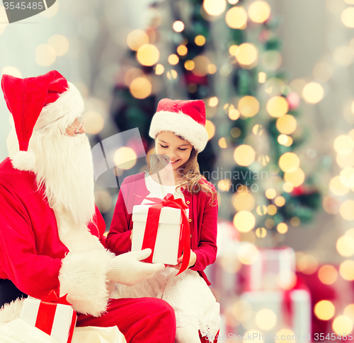 Image of smiling little girl with santa claus and gifts