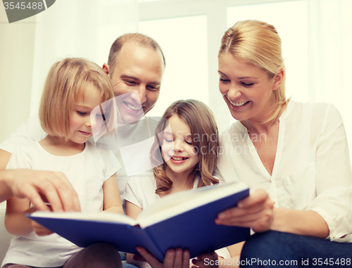 Image of smiling family and two little girls with book