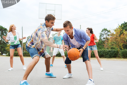 Image of group of happy teenagers playing basketball