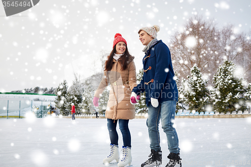 Image of happy couple ice skating on rink outdoors