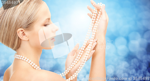 Image of beautiful woman with sea pearl necklace over blue