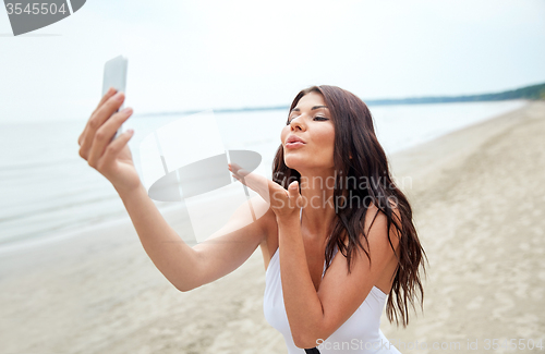 Image of young woman taking selfie with smartphone