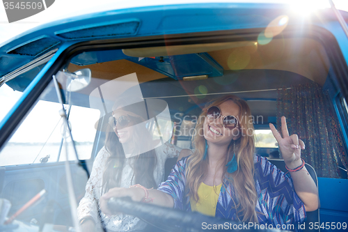 Image of smiling young hippie women driving minivan car