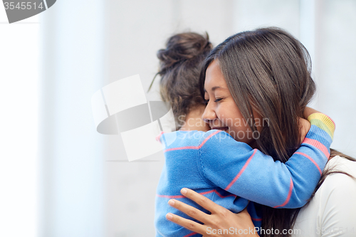 Image of happy mother and daughter hugging at home