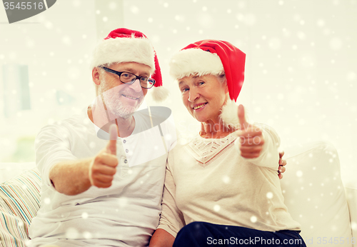 Image of happy senior couple in santa helper hats at home