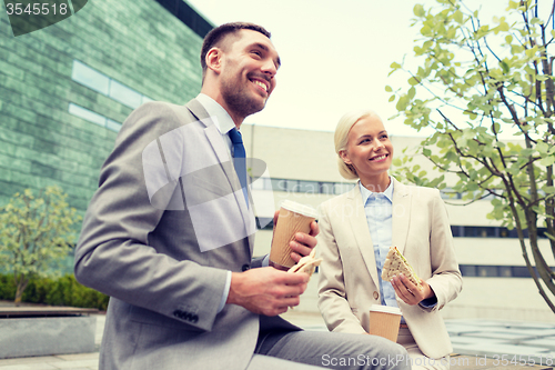 Image of smiling businessmen with paper cups outdoors