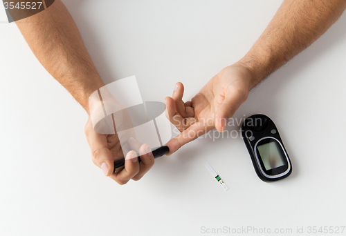 Image of close up of man checking blood sugar by glucometer