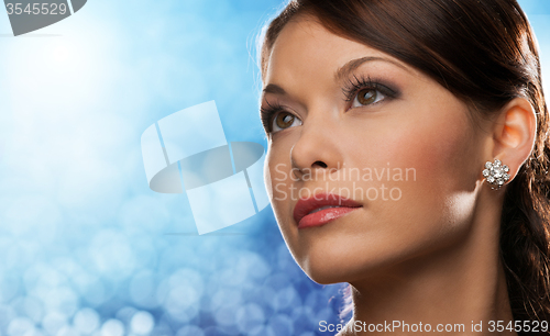 Image of woman with diamond earring over blue lights