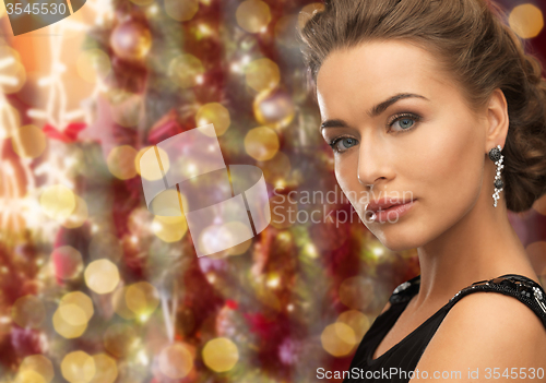 Image of beautiful woman wearing earrings over lights