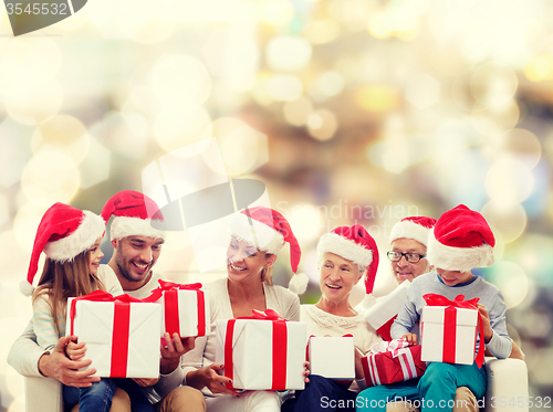 Image of happy family in santa helper hats with gift boxes