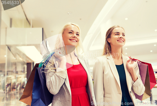 Image of happy young women with shopping bags in mall