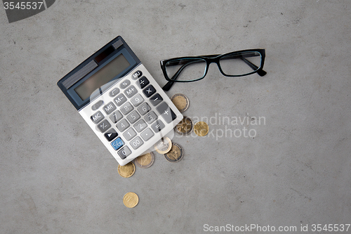 Image of calculator, eyeglasses and euro coins on table