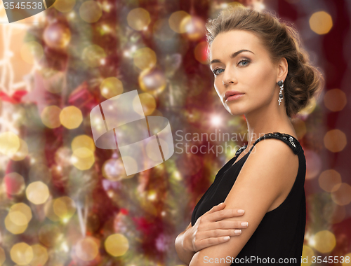 Image of beautiful woman wearing earrings over lights