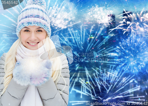 Image of happy young woman in winter clothes over firework