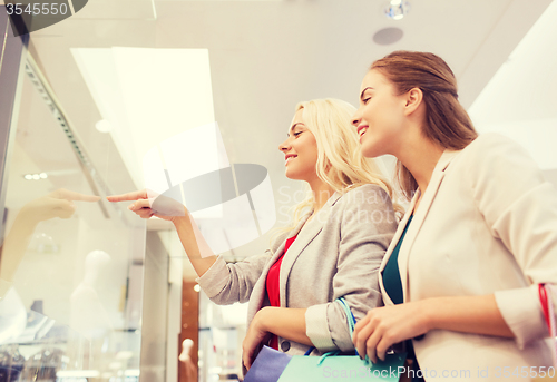 Image of happy young women with shopping bags in mall