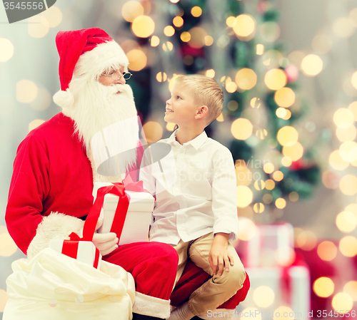 Image of smiling little boy with santa claus and gifts