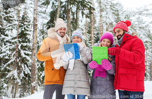 Image of smiling friends with tablet pc in winter forest