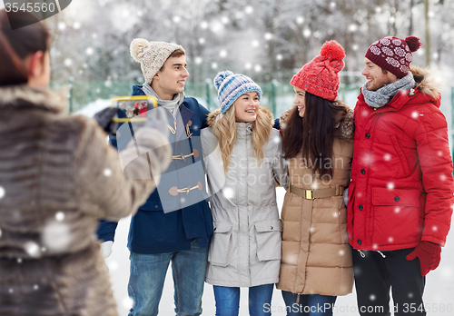 Image of happy friends taking picture with smartphone