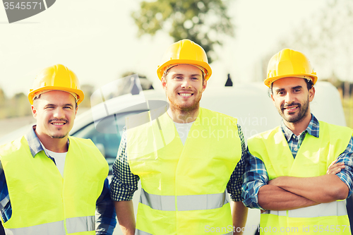 Image of group of smiling builders in hardhats outdoors