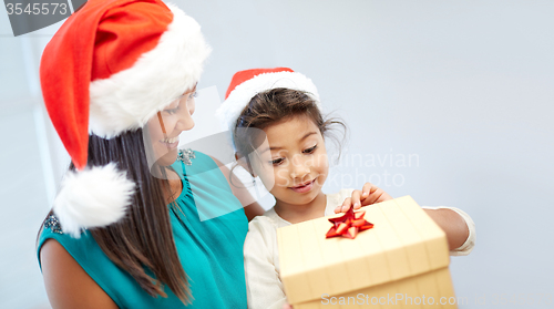 Image of happy mother and child in santa hats with gift box