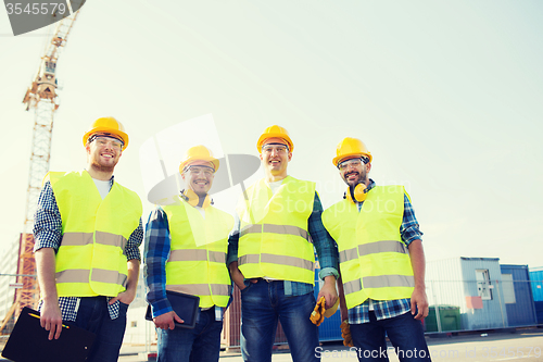 Image of group of smiling builders with tablet pc outdoors