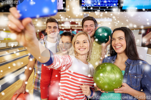 Image of happy friends with smartphone in bowling club