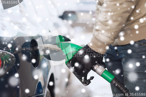 Image of close up of man with fuel hose nozzle tanking car