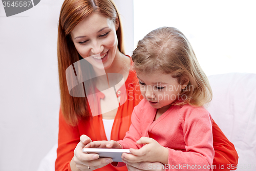 Image of happy mother and daughter with smartphone at home