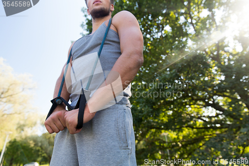 Image of young man exercising with expander in summer park