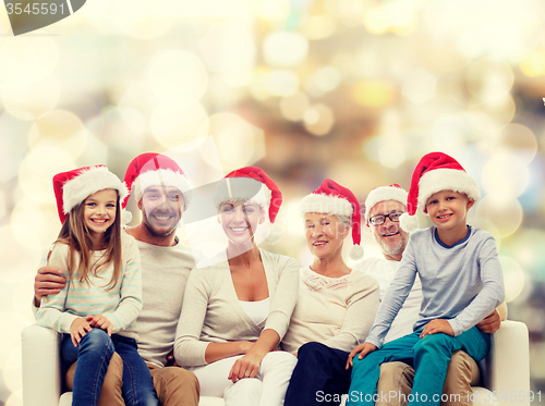 Image of happy family in santa helper hats sitting on couch