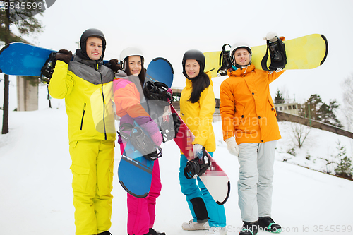 Image of happy friends in helmets with snowboards outdoors