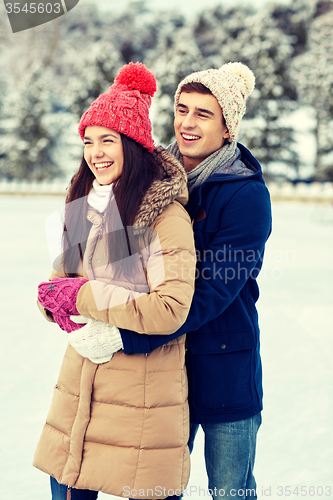 Image of happy couple ice skating on rink outdoors