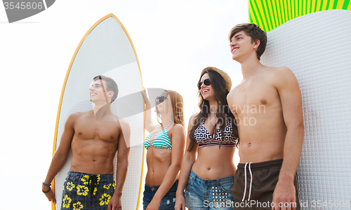 Image of friends in sunglasses with surfboards on beach