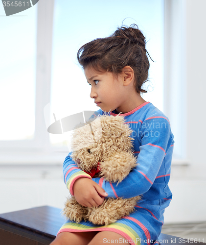 Image of sad little girl with teddy bear toy at home