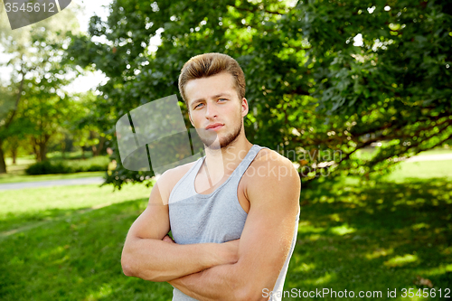 Image of sporty young man with crossed arms at summer park