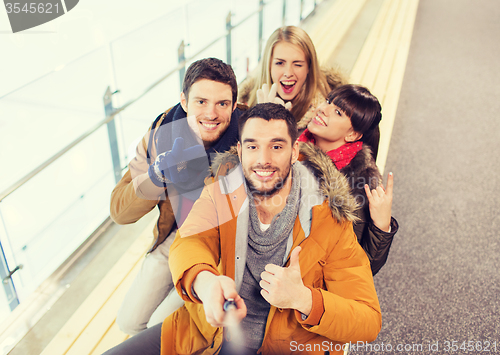 Image of happy friends taking selfie on skating rink