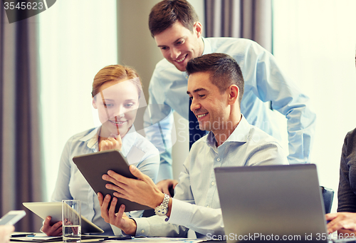 Image of smiling business people with tablet pc in office