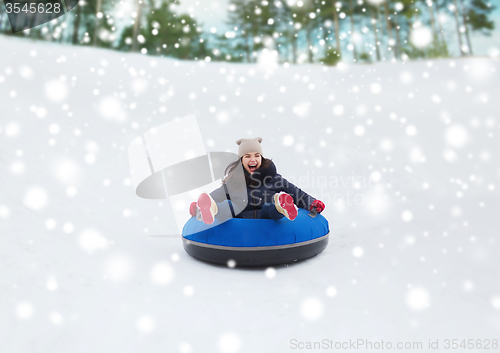 Image of happy teenage girl sliding down on snow tube