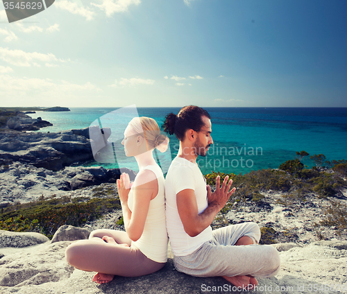 Image of smiling couple making yoga exercises outdoors