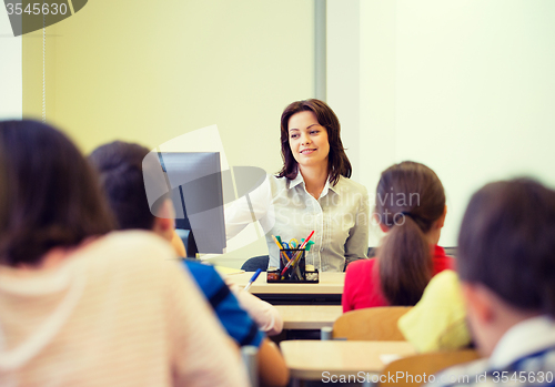 Image of group of school kids raising hands in classroom