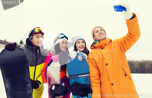 Image of happy friends with snowboards and smartphone