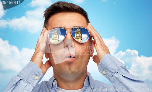 Image of face of man in sunglasses looking at big ben tower