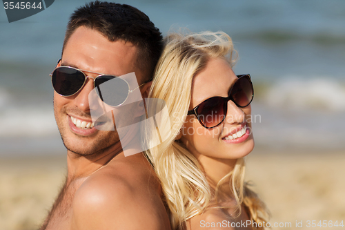 Image of happy couple in swimwear sitting on summer beach