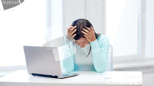 Image of businesswoman with laptop and papers in office