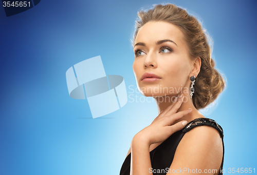 Image of beautiful woman wearing earrings over blue
