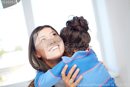 Image of happy mother and daughter hugging at home