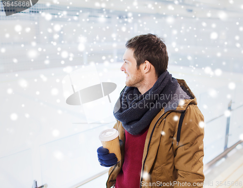 Image of happy young man with coffee cup on skating rink