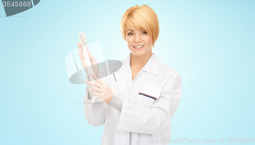 Image of happy female doctor with big toothbrush