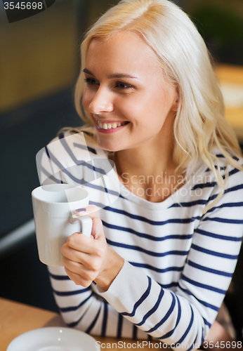 Image of happy young woman drinking tea or coffee