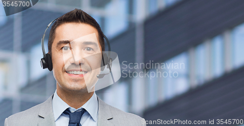 Image of happy businessman in headset over business center